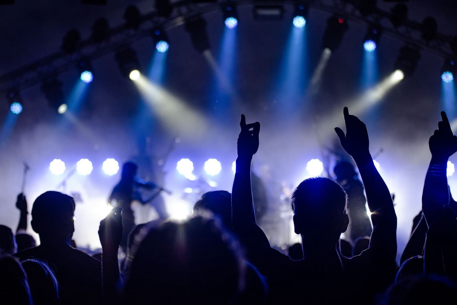 Crowd with hands up under stage lights at a live event