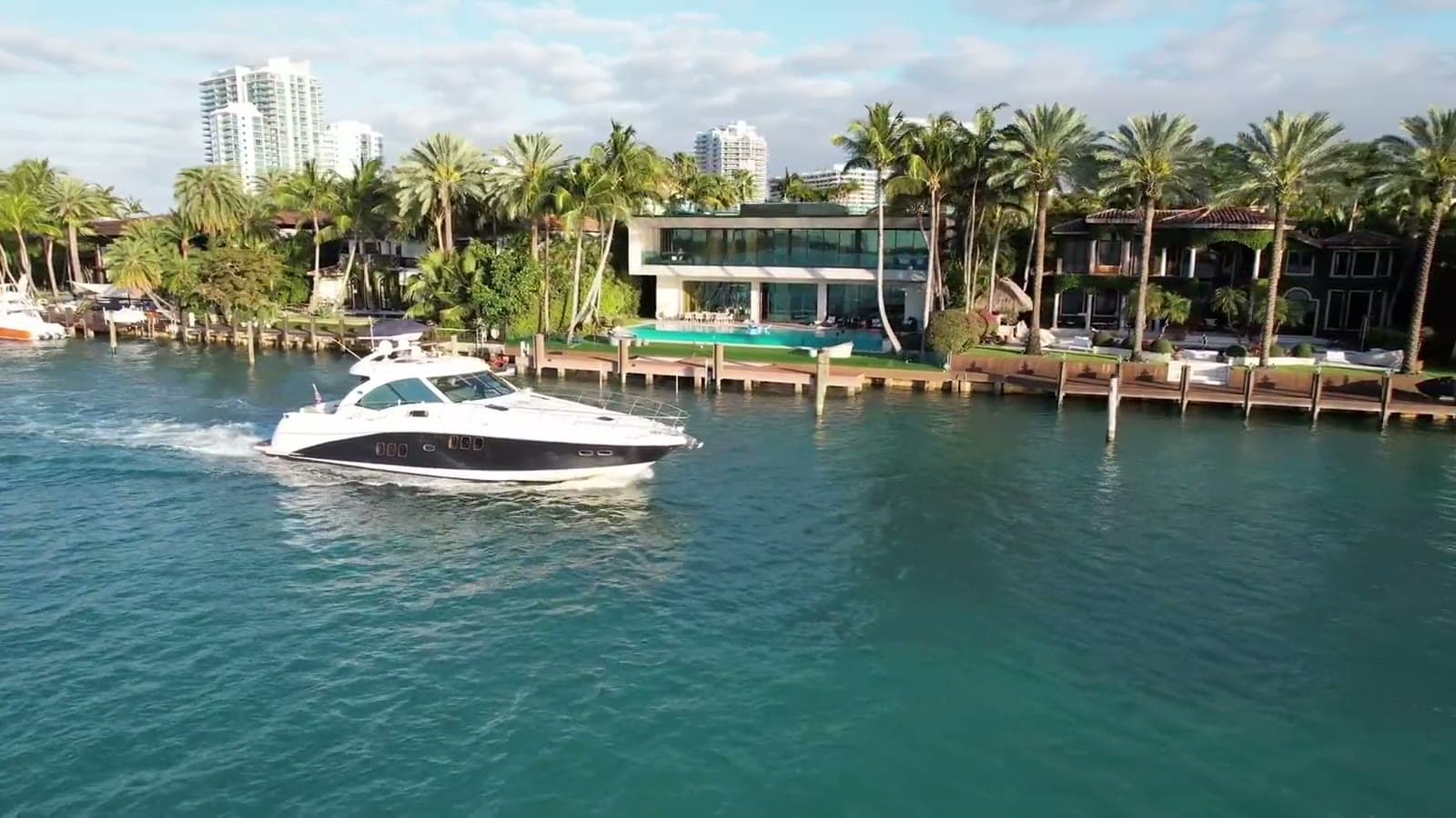 A private boat underway past waterfront homes and palms in Miami Beach