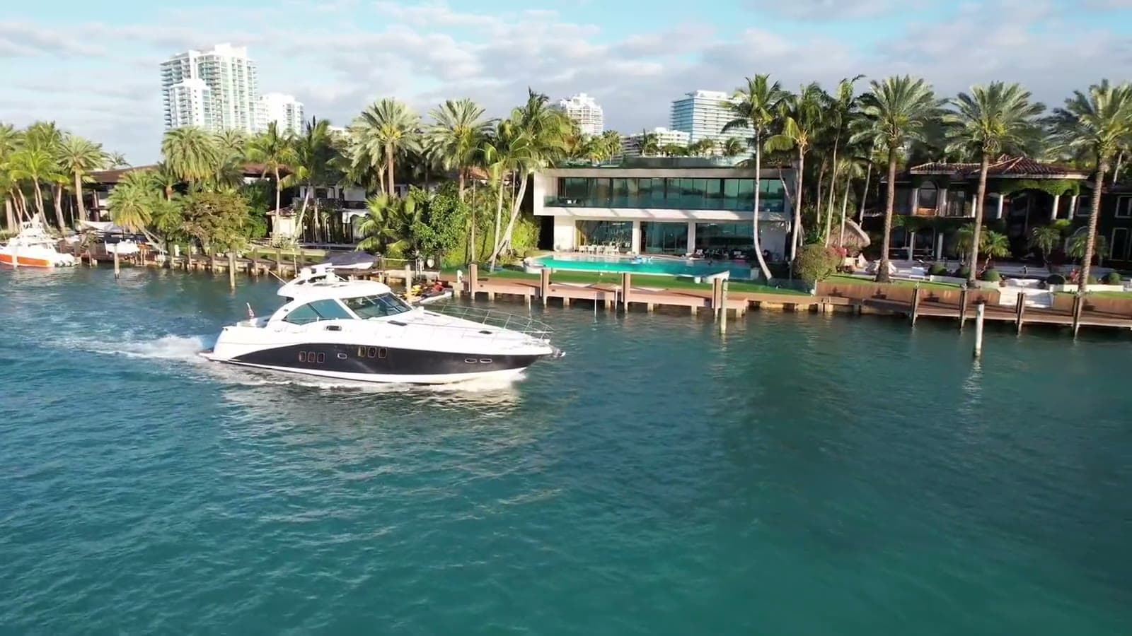 A modern waterfront home in Miami Beach with a pool and its own dock, a boat passing on the bay